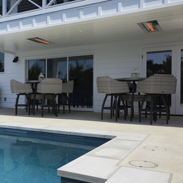 Outdoor dining area with wicker chairs and a table near a swimming pool, featuring a covered patio and heating lamps for comfort.