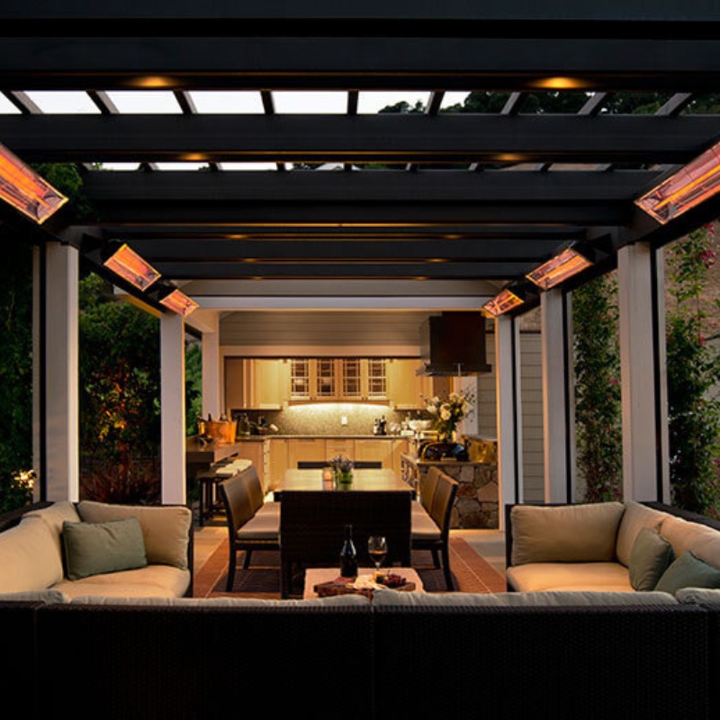 Cozy outdoor living space featuring a modern pergola with heating lamps, stylish seating, and an illuminated kitchen in the background. Perfect for entertaining and relaxation.