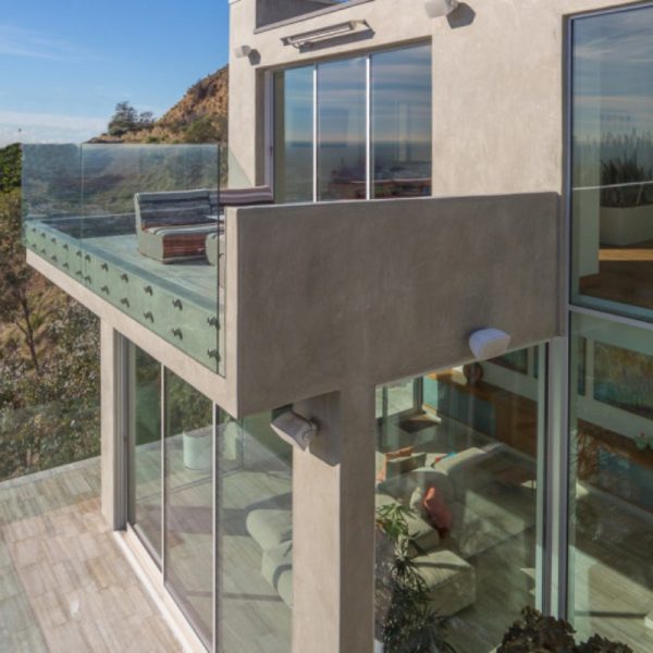 Modern balcony with glass railing overlooking scenic landscape, featuring outdoor seating and contemporary architecture.