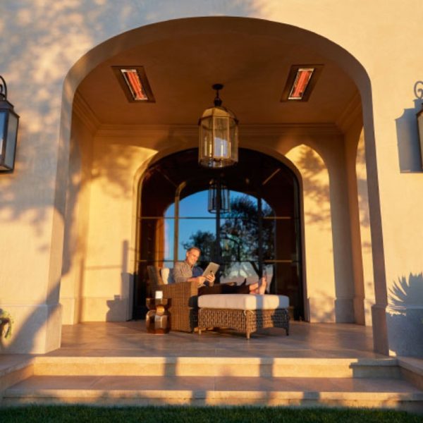 Man reading a book on a stylish outdoor patio, illuminated by sunset, with modern lighting fixtures and a cozy atmosphere.