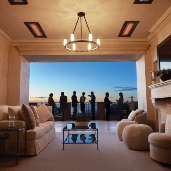 Elegant indoor living space with modern decor, featuring a cozy sofa and stylish coffee table, overlooking a sunset view with silhouettes of people enjoying the scenery on the balcony.