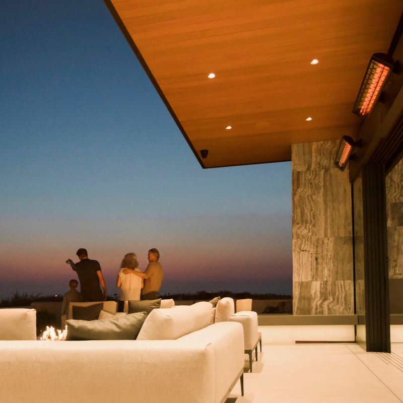 Modern outdoor living space with cozy seating, overlooking a sunset gathering of four people enjoying a warm evening.