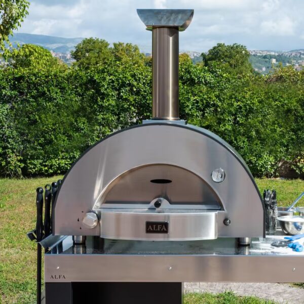 Outdoor pizza oven with stainless steel design and chimney, set in a green backyard environment.