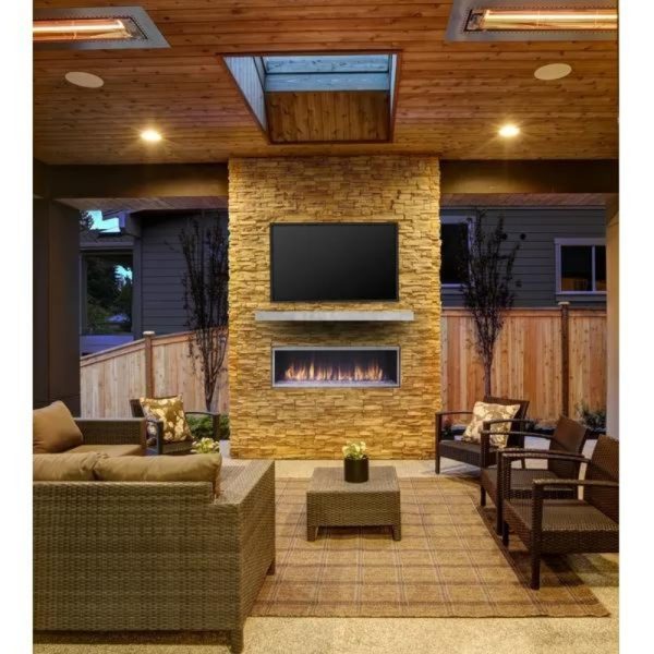 Cozy outdoor living space featuring a stone fireplace, mounted TV, and comfortable seating arrangements with modern decor.