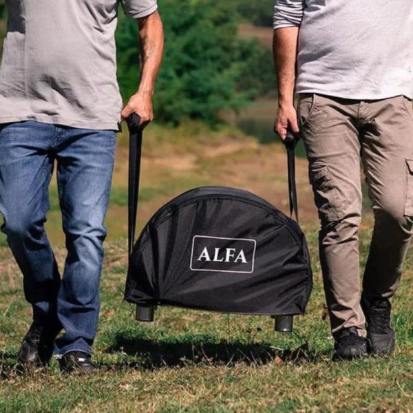 Two men carrying a portable ALFA grill in a black carrying bag while walking on grassy terrain.