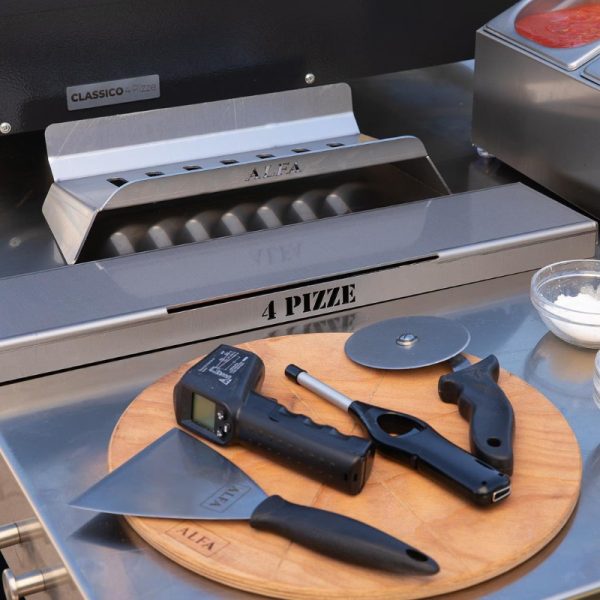 Stainless steel pizza oven with tools including a pizza cutter, heat gun, and preparation surface for making pizza.