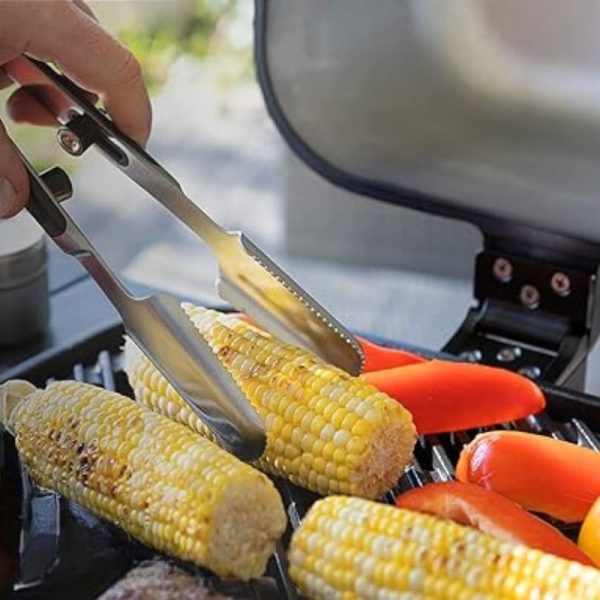 Grilling corn on the cob and red bell peppers with stainless steel tongs on a barbecue grill.