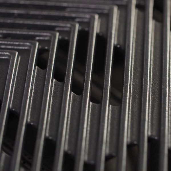 Close-up of stacked black metal sheets with slotted openings, showcasing a textured surface and geometric patterns.