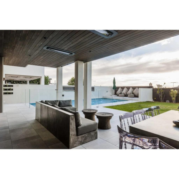 Modern outdoor living space featuring a sleek patio with a contemporary sofa, stylish side tables, and a dining area. The backdrop includes a swimming pool with water features, surrounded by landscaped greenery and comfortable seating.