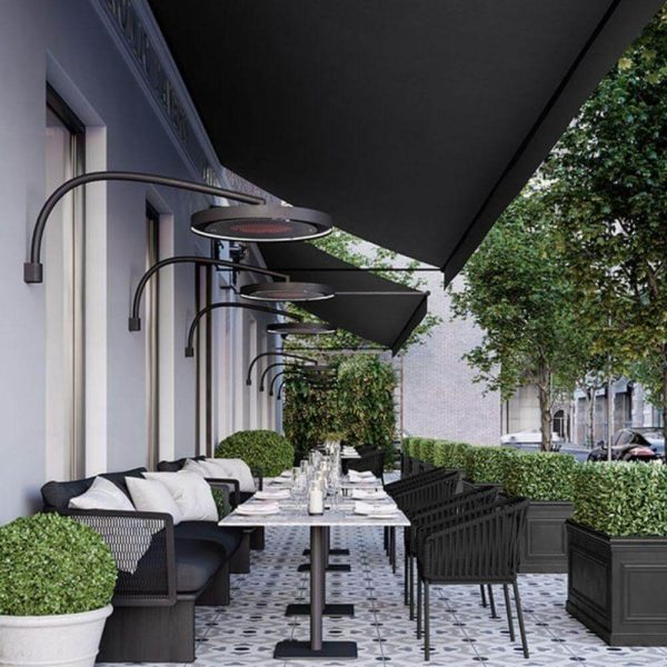 Outdoor restaurant patio featuring modern black furnishings, overhead heaters, and lush greenery, designed for an inviting dining experience.