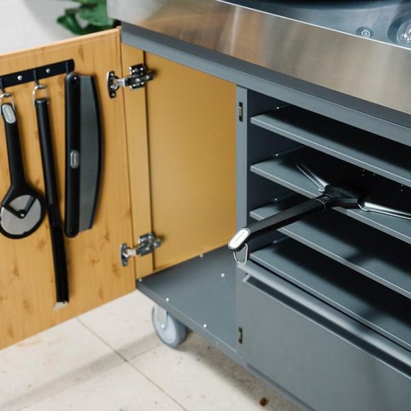 Storage cart with open cabinet door displaying grilling tools and accessories, featuring a sleek metal top and multiple shelves.