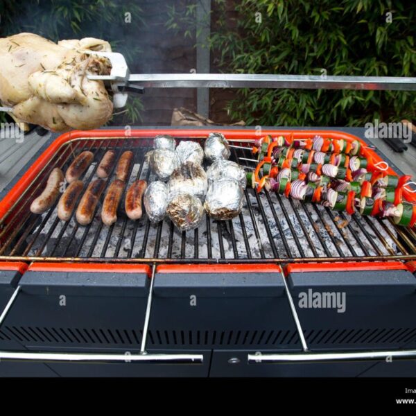 Grilled chicken, sausages, foil-wrapped potatoes, and vegetable skewers cooking on a barbecue grill.