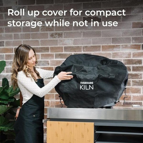 Woman using a roll-up cover for compact storage of the Everdure Kiln, showcasing functionality and convenience in a modern kitchen setting.