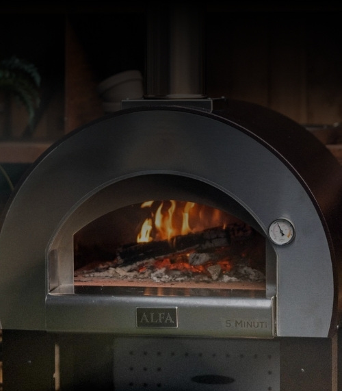 Wood-fired pizza oven with visible flames and temperature gauge, designed for quick cooking in five minutes.