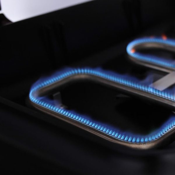 Close-up of a gas burner with blue flames ignited, showcasing the heating element on a modern kitchen stove.
