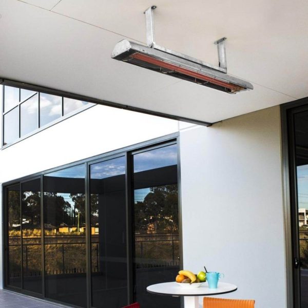 Hanging outdoor infrared heater mounted on a modern patio ceiling, providing warmth to a dining area with a round table and fruit.