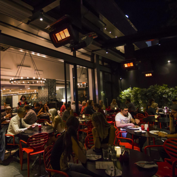Busy restaurant interior at night with diners enjoying meals, red chairs, and ambient lighting.