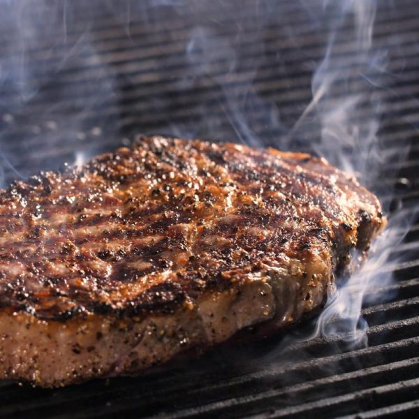 Grilled steak on a barbecue grill, showcasing a smoky flavor and charred texture.
