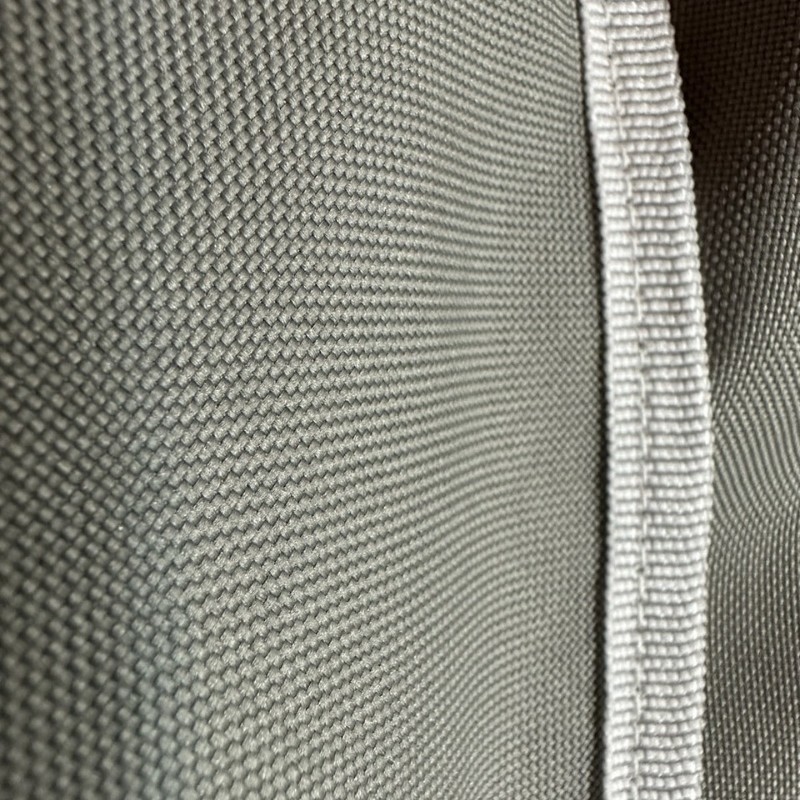 Close-up of textured gray fabric with a white seam, showcasing the weave pattern and material details.