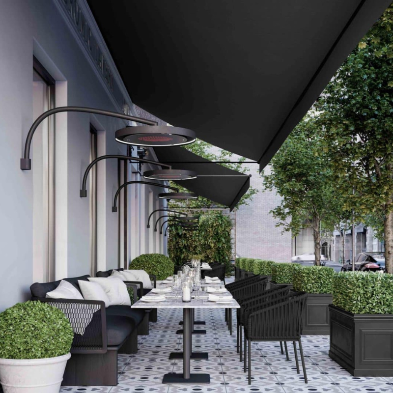 Stylish outdoor restaurant patio featuring modern seating, elegant table settings, and overhead heating lamps, surrounded by lush greenery and decorative planters.