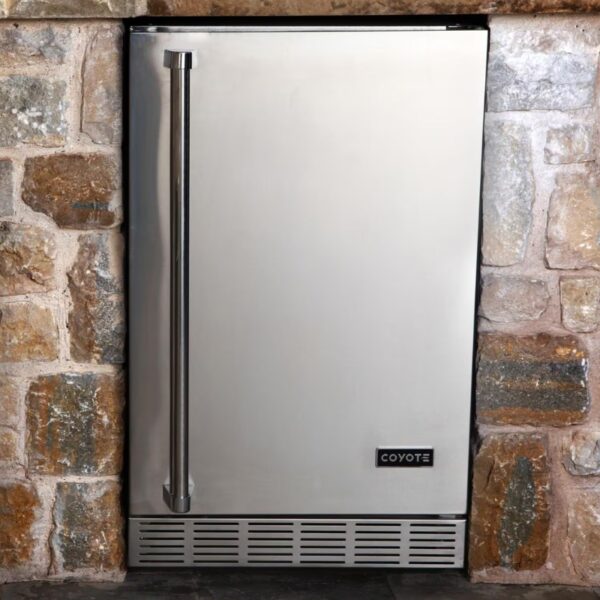 Stainless steel Coyote outdoor refrigerator built into a stone wall, designed for durability and convenience in outdoor kitchens.