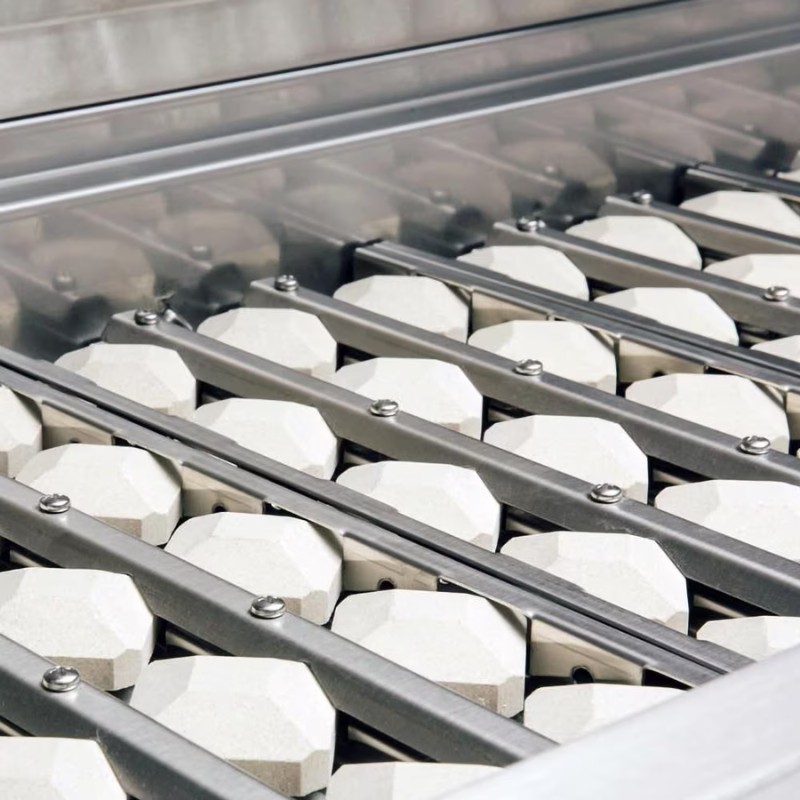 Industrial equipment featuring a close-up of a stainless steel conveyor system with octagonal white components, designed for efficient material handling in manufacturing processes.