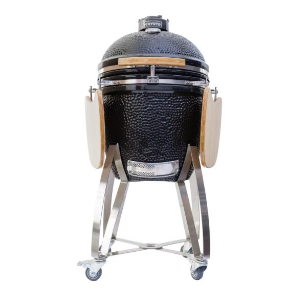 Coyote ceramic grill with wooden side shelves, featuring a stainless steel base and wheels for easy mobility. Ideal for outdoor cooking and barbecuing.