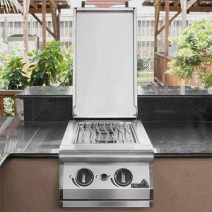 Stainless steel outdoor grill with an open lid, featuring multiple burners and a sleek countertop design, surrounded by greenery.