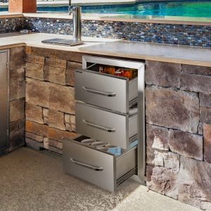 Stainless steel outdoor kitchen drawers integrated into a stone wall, showcasing organized storage for beverages and kitchen essentials.