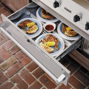 Grill drawer with plates of grilled chicken, corn, and toast, showcasing a Viking kitchen appliance.