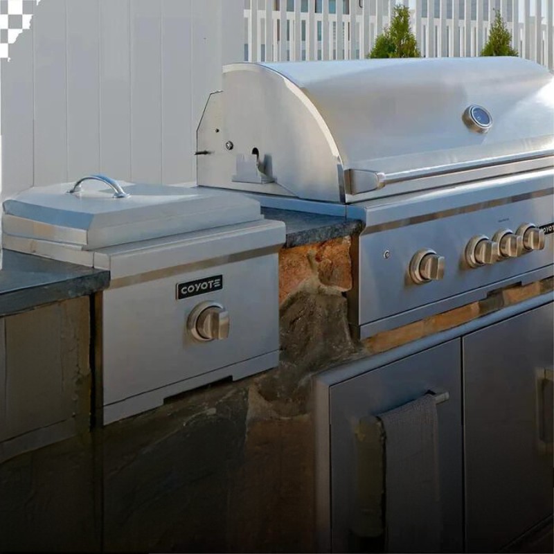 Stainless steel outdoor kitchen setup featuring a Coyote grill and storage unit, ideal for barbecuing and entertaining.