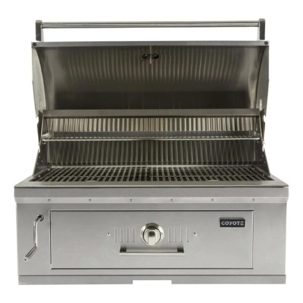 Stainless steel Coyote gas grill with open lid, featuring two cooking grates and a storage drawer for outdoor cooking.