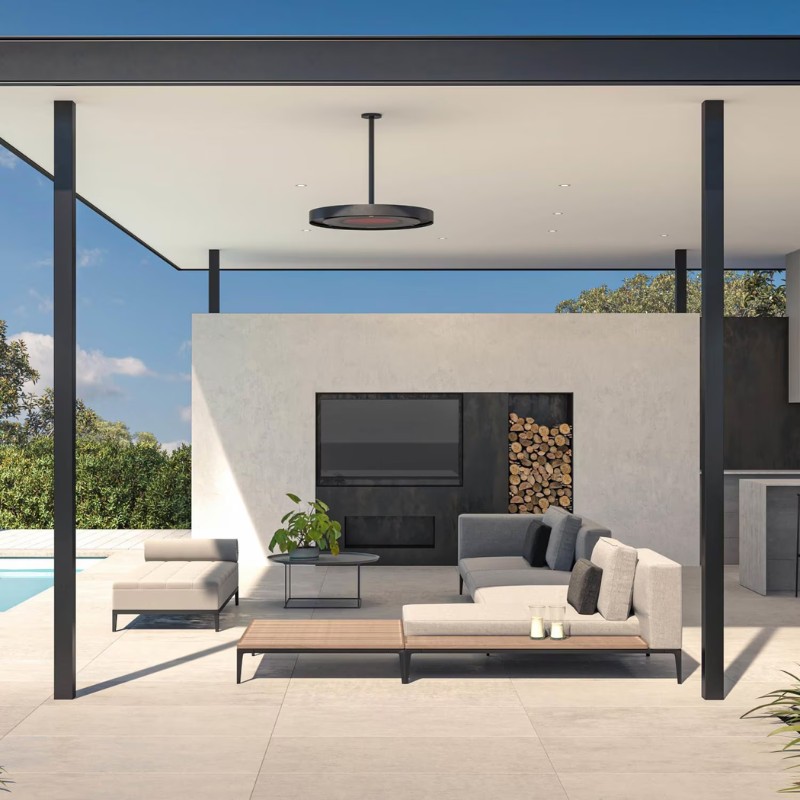 Modern outdoor living space featuring a stylish lounge area with a sectional sofa, coffee table, and decorative plants, set against a backdrop of a sleek wall-mounted TV and stacked firewood. Bright blue sky and swimming pool enhance the serene ambiance.