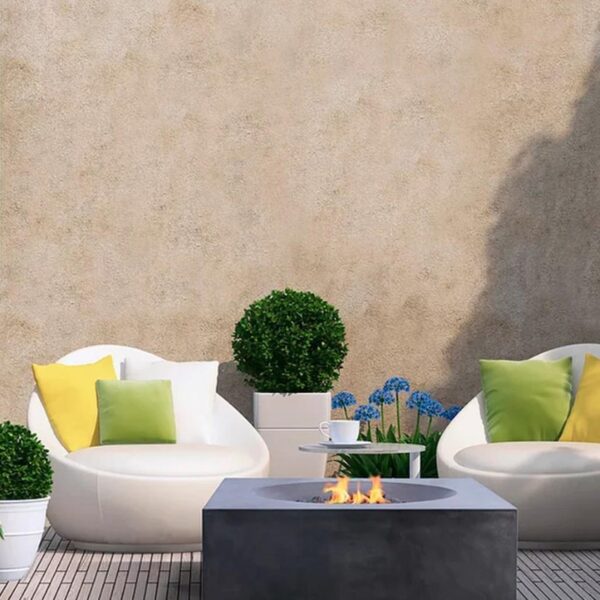 Modern outdoor seating area featuring white chairs with colorful cushions, a fire pit, and potted plants against a textured wall.