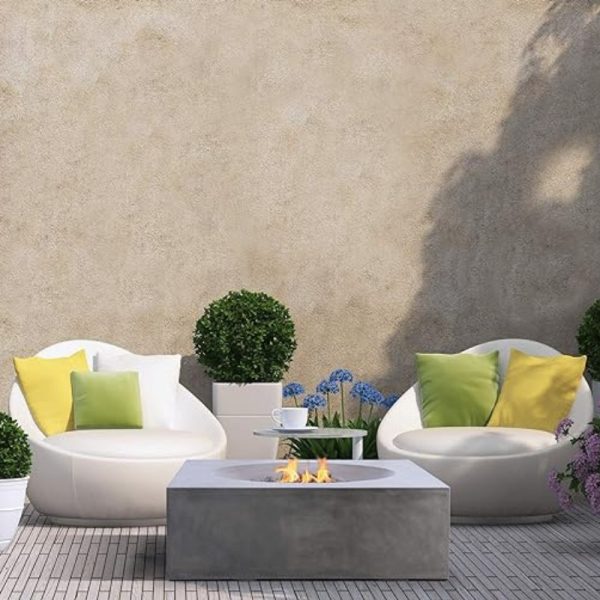 Modern outdoor seating area with two white chairs, colorful cushions, a concrete fire pit, and potted plants, creating a cozy ambiance.