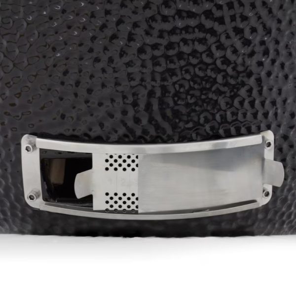 Close-up of a black textured surface with a metallic plate featuring perforations, likely part of a design element or functional accessory.