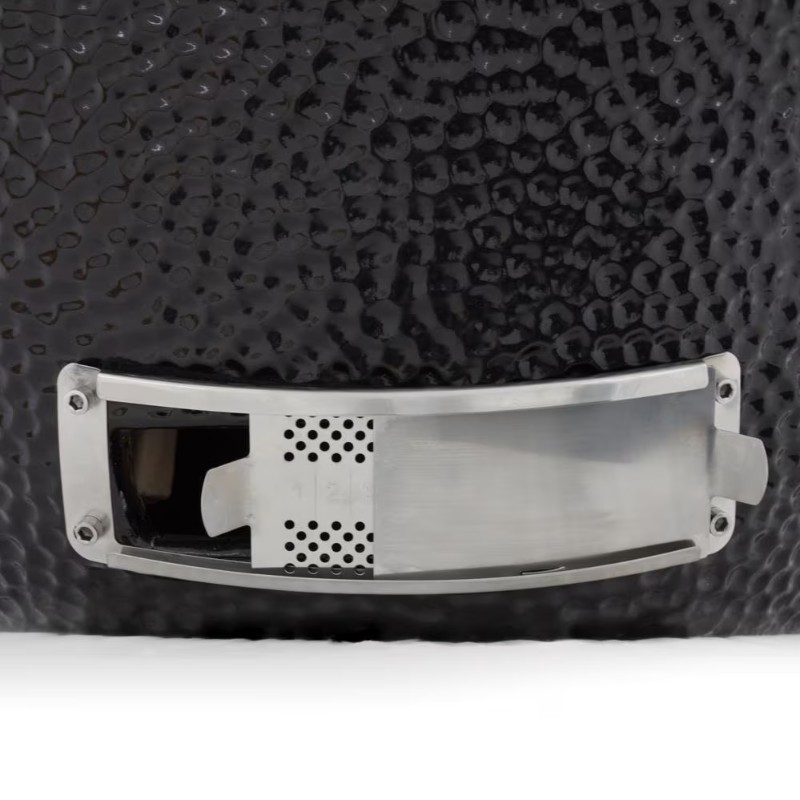 Close-up of a black textured surface with a metallic plate featuring perforations, likely part of a design element or functional accessory.