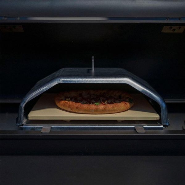 Pizza baking in an oven with a metal cover and a stone baking surface, showcasing a golden crust and toppings.