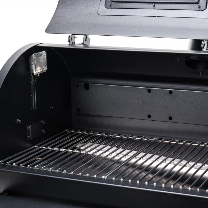 Interior view of a black grill with a stainless steel cooking grate and built-in light, showcasing ample cooking space and ventilation.