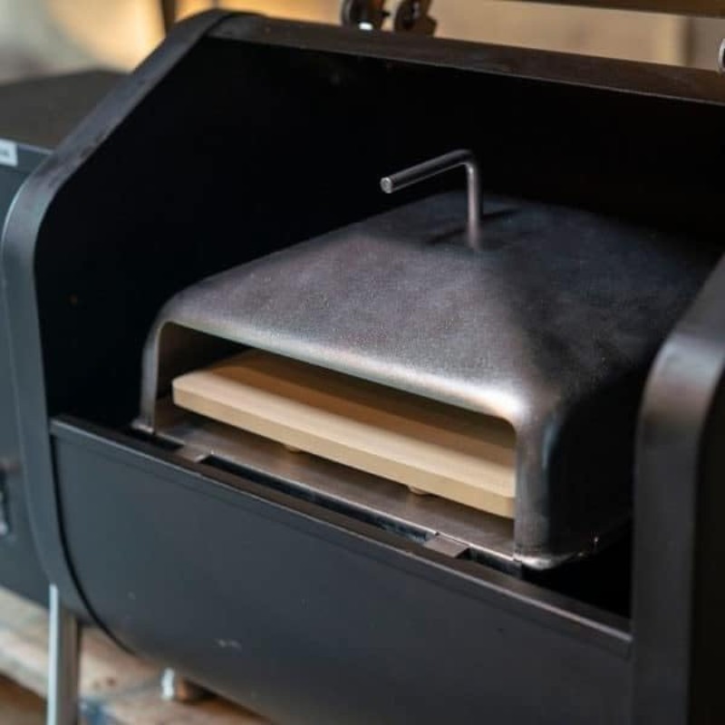 Close-up of a pizza oven with a stone baking surface, featuring a sleek black design and a handle for easy access.