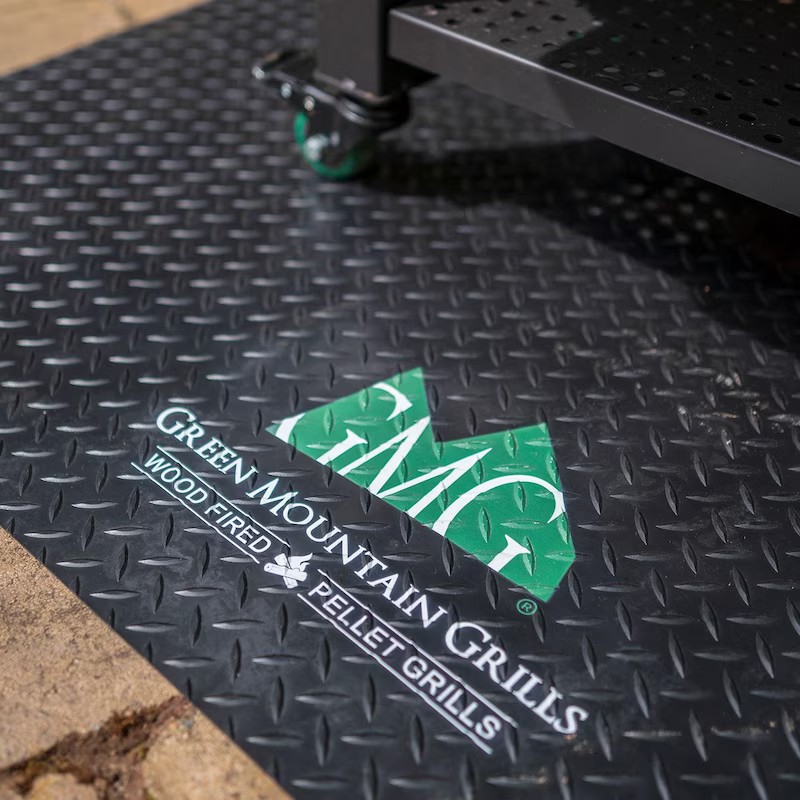 Close-up of a textured black mat featuring the Green Mountain Grills logo, highlighting "Wood Fired Pellet Grills," ideal for outdoor cooking enthusiasts.