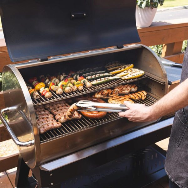 Person grilling a variety of meats and vegetables on a barbecue grill, showcasing a delicious outdoor cooking scene.