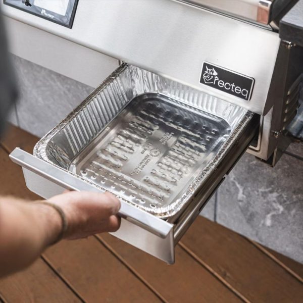 Hand reaching for a stainless steel pellet grill drawer with a removable aluminum tray inside, designed for easy cooking and cleanup.
