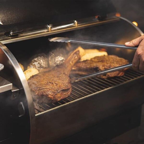 Grilling juicy steaks and corn on a barbecue, with steam rising from the hot grill.