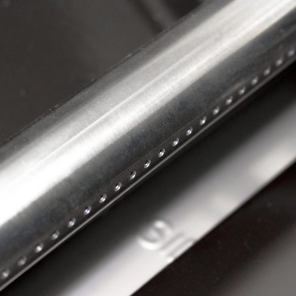 Close-up of a polished stainless steel surface with small holes, showcasing a modern design and sleek finish, ideal for kitchen or industrial use.