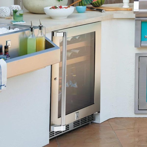 Outdoor kitchen featuring a stainless steel beverage refrigerator with a glass door, adjacent to a stylish sink with various bottles and a bowl of fresh salad. Ideal for entertaining guests.