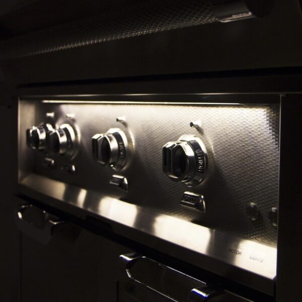Close-up of modern stainless steel oven knobs with illuminated controls, highlighting high-end kitchen appliances.