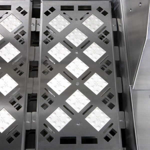 Close-up of a stainless steel industrial tray with a diamond-patterned surface, featuring white textured inserts for grip and stability.