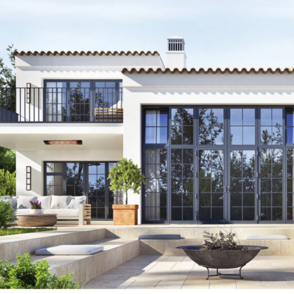 Modern two-story house with large windows, a balcony, and a landscaped outdoor area featuring a fire pit and seating.