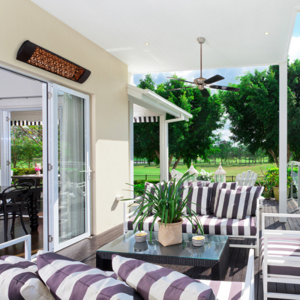 Stylish outdoor patio with striped cushions, a glass coffee table, and a ceiling fan, surrounded by lush greenery.
